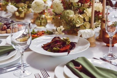 Estetik stil sonbahar sofrası, doğal ışık altında düzenlenmiş çiçekler ve mumlar. Konforlu tatil tablosu.