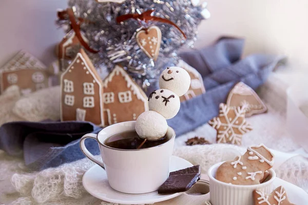 Winter aesthetic morning. Marshmallow snowman in hot chocolate, ginger cookies near Christmas tree. Cozy warm home.