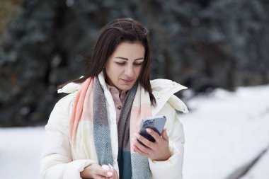 Dışarıda cep telefonu ve kulaklık kullanan bir kadın. Serbest çalışma, uzaktan çalışma konsepti.