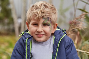 Yeni yıl 2024 maskeli balosu. Yüzünde ejderha resmi olan bir çocuk. Geleneksel Çin takviminin sembolü.