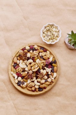 Yukarıdan doğal bir arka planda karışık fındıklı ahşap kase. Sağlıklı yiyecek ve atıştırmalıklar. Ceviz, badem, fındık ve kaju. Kuru üzüm ve kızılcık.