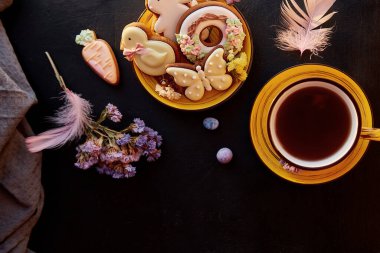 Paskalya estetiği ev yapımı kurabiyeler, çay fincanı dairesi dekorasyonlu. Tatil yemeği, siyah arka planda çay saati..