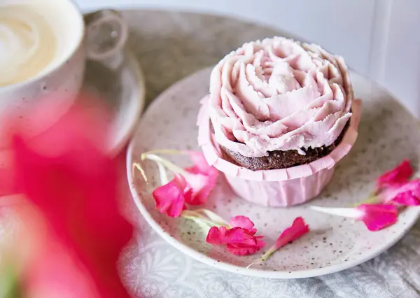 Aesthetic pink cupcake with cup of coffee. Flowers decoration. Escapism dreamy desserts. Holiday background.