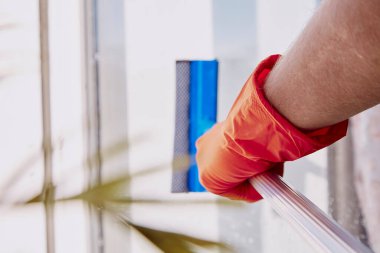 Bahar temizliği konsepti. Adam camları yıkıyor. Ev işleri işte. Boyutsal bitki, katmanlar, bulanık önplan.