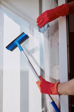 Adam pencereleri yıkıyor, daireyi temizliyor. Bahar temizliği konsepti. Ev işleri işte. Koronavirüs nedeniyle karantina sırasında dezenfeksiyon