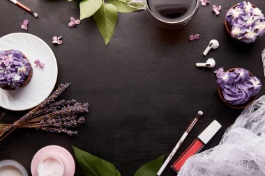 Merkezinde fotokopi alanı olan kadınsı estetik arka plan. Mor çiçekli kekler, bir fincan kahve, yüz kremi, kulaklık ve lavanta..