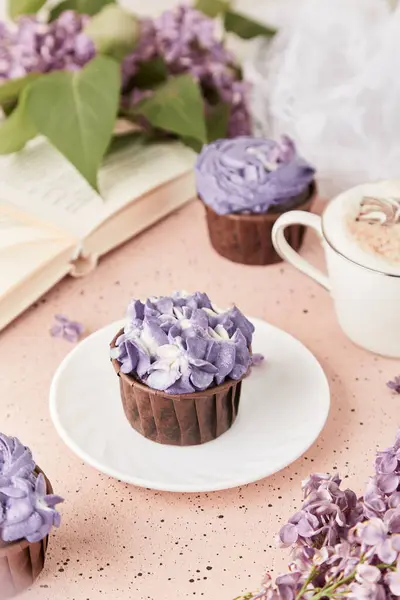 Aesthetic female lifestyle. Book and purple floral cake. Violet sweet no sugar dessert among lilac flowers.