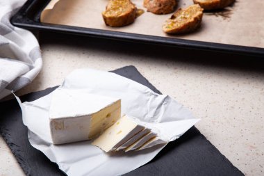 Zanaatkar Brie peyniri taze fırınlanmış ekmek dilimlerinin yanında zarif bir şekilde sergilenir.