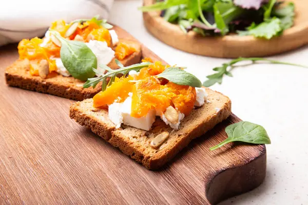 Gourmet open sandwich with spiced pumpkin, crumbled feta, and roasted seeds, perfect for a fall-inspired brunch or snack