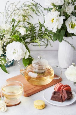 Sabah estetik masası. Çaydanlık, fincan, badem kurabiyesi, çikolata, beyaz çiçekler. Kendine zaman ayır. Yaşam tarzı kavramı