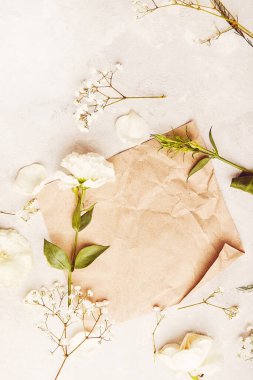 Beyaz çiçekler arasında kağıt bej şablon. Davetiye, kartpostal, metin ve üst görünüm için estetik rustik vintage arkaplan.