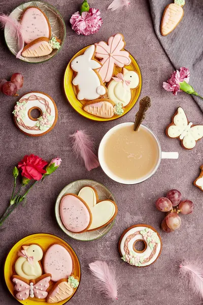 Aesthetic happy Easter background, coffee time top view. Decorated glazed cookies, coffee, feathers flat lay. Spring background.