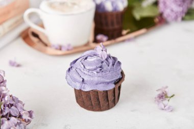 Leylak çiçeklerinin arasında mor kek. Estetik tatlılar ve kahve fincanı. Bahar arkaplanı.