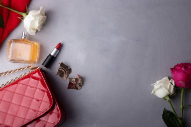 Rafine güzellik ürünleri, modaya uygun çanta düzeneği, gül ve makyajlı moda ayrıntıları. Estetik arka plan. Boşluğu kopyala.