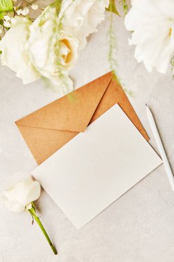 Selamlar, davetiyeler, kartpostallar, beyaz çiçeklerin arasındaki mesajlar için bej renkli kağıt zarf. Biyofilik iç mekan, rahat ev. Boşluğu kopyala