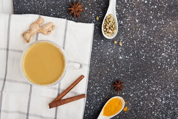 Traditional healthy masala tea - indian drink with spices turmeric, star anise, cardamom on the cozy kitchen with copy space.