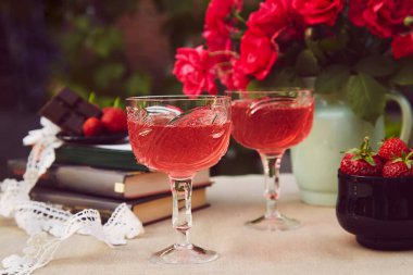 Birkaç kadeh kırmızı ev yapımı şarap. Çilek ezmesi. Gül buketi. Estetik yaz masa ayarları