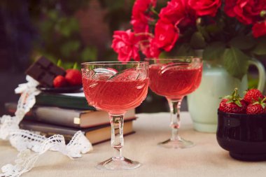 Birkaç kadeh kırmızı ev yapımı şarap. Çilek ezmesi. Gül buketi. Estetik yaz masa ayarları