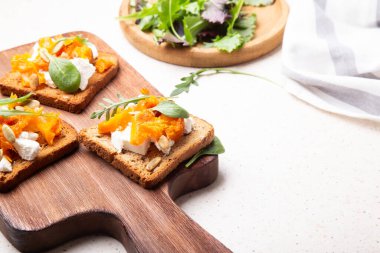 Kızarmış balkabağı, kremalı keçi peyniri ve sağlıklı bir vejetaryen yemeği için yeşil yapraklı tam tahıllı ekmek..