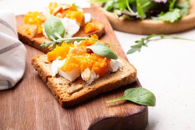 Taze yeşilliklerle süslenmiş tam tahıllı ekmeğin üzerinde kabak ve peynirli tost..