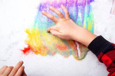 Beyaz arka planda gökkuşağı renkli pudra ile çocuk el boyası.