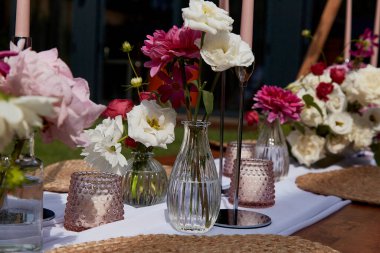 Taze çiçekler ve bulaşık takımlarıyla şık masaları. Yaz partisi pikniği için görsel masa düzenleme, etkinlik planlama ve estetik tasarım