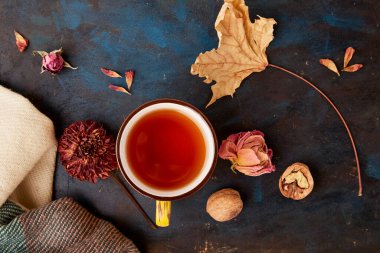 Kuru güllerin ve yaprakların arasında sonbahar esinlenilmiş sıcak sonbahar çay fincanı. Estetik sonbahar titreşimleri arkaplan.