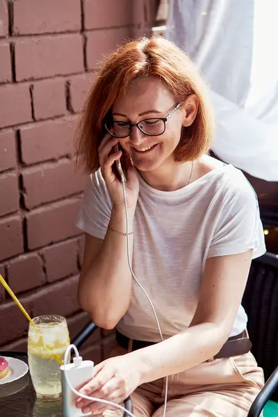 stock image On-the-go charging a distance worker uses a powerbank while enjoying a refreshing cocktail.