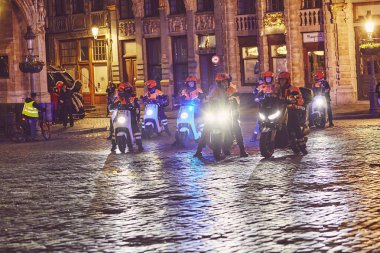 Brussels, Belgium - June, 1: Group of police officers on motorbikes patrolling the city streets at night before a major event. clipart