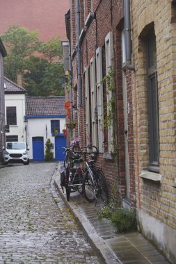 Dar antik cadde. Bisikletler yağmurlu bir günde kaldırım taşlı bir yola park edildi.