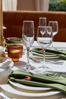 Tabaklar, bardaklar, peçeteler ve mumlarla dolu bir masa..