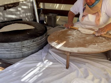 Gozme, Türk sokak pazarında yemek pişirme sahnesi. Yerel satıcı otantik gözleme ekmeği hazırlar, kadın hamur işini halleder..