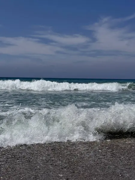 Parlak güneş ışığı altında ışıldayan deniz dalgaları. Işıldayan okyanus yüzeyi, güneşte parlayan yumuşak dalgalarla, sahilde sakin bir yaz gününün güzelliğini yakalıyor.