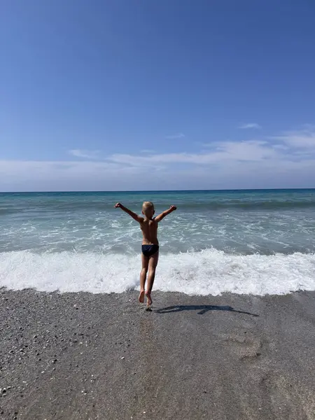 Deniz kenarında oynayan mayolu mutlu çocuk. Yaz tatilleri.