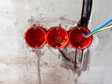 Beton bir duvarın içindeki gelecek prizler için duvara monte edilmiş kablolar. Daire inşası, ham alan ve altyapı aşaması kavramı