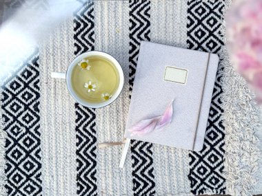 Defterin yanında bir fincan papatya çayı. Yavaş yaşam, günlük tutma, farkındalık ve barışçıl kişisel bakım.. 