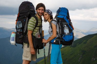 Sırt çantalı, sevgi dolu bir çift Karpat Dağları 'nın çarpıcı zeminine karşı baş başa, sırılsıklam aşık bir şekilde ayakta duruyor.