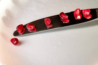 Reflective Harmony: Pomegranate Seeds on Knife.  Scattered pomegranate seeds reflecting on a sleek knife blade, arranged with abstract precision to symbolize the ordering. clipart