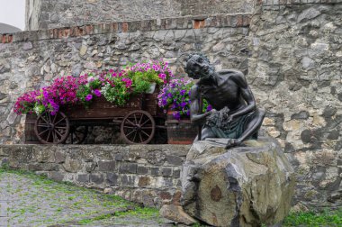 Historic Sculpture of a Seated Figure with a Flower Cart in a Medieval Courtyard clipart