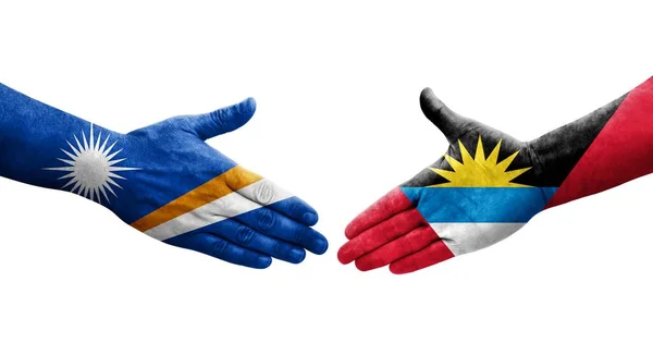 stock image Handshake between Antigua and Barbuda and Marshall Islands flags painted on hands, isolated transparent image.