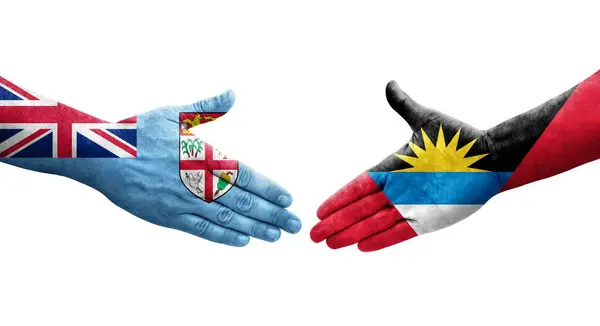 Stock image Handshake between Antigua and Barbuda and Fiji flags painted on hands, isolated transparent image.