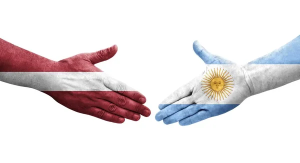 手に描かれたアルゼンチンとラトビアの旗の間の握手 孤立した透明なイメージ — ストック写真