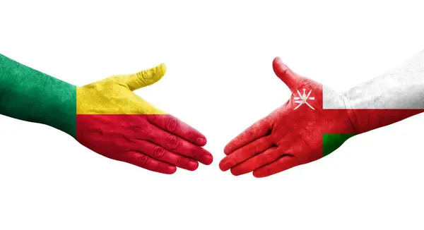 Stock image Handshake between Benin and Oman flags painted on hands, isolated transparent image.