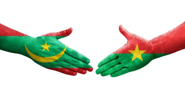 stock image Handshake between Burkina Faso and Mauritania flags painted on hands, isolated transparent image.