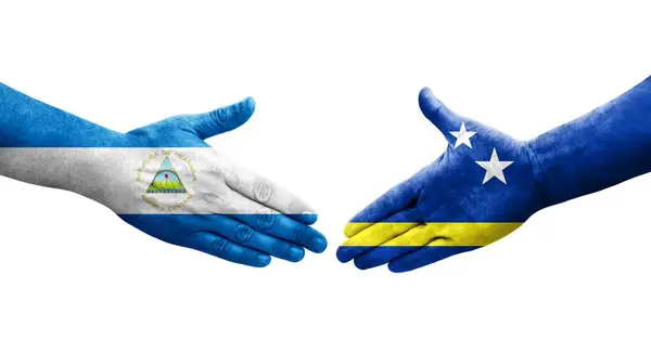 Stock image Handshake between Curacao and Nicaragua flags painted on hands, isolated transparent image.