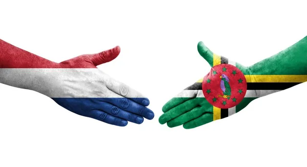 stock image Handshake between Dominica and Netherlands flags painted on hands, isolated transparent image.