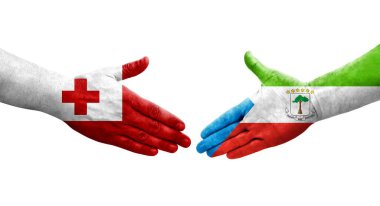 Ellerine boyanmış Ekvator Ginesi ve Tonga bayrakları arasındaki el sıkışma, izole şeffaf görüntü.