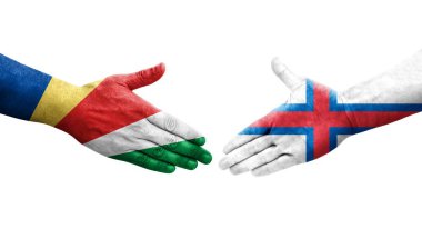 Faroe Adaları ve Seyşeller arasındaki el sıkışma ellerinde boyanmış bayraklar, izole şeffaf görüntü.