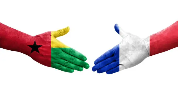 Stock image Handshake between France and Guinea Bissau flags painted on hands, isolated transparent image.