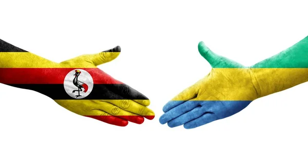 stock image Handshake between Gabon and Uganda flags painted on hands, isolated transparent image.